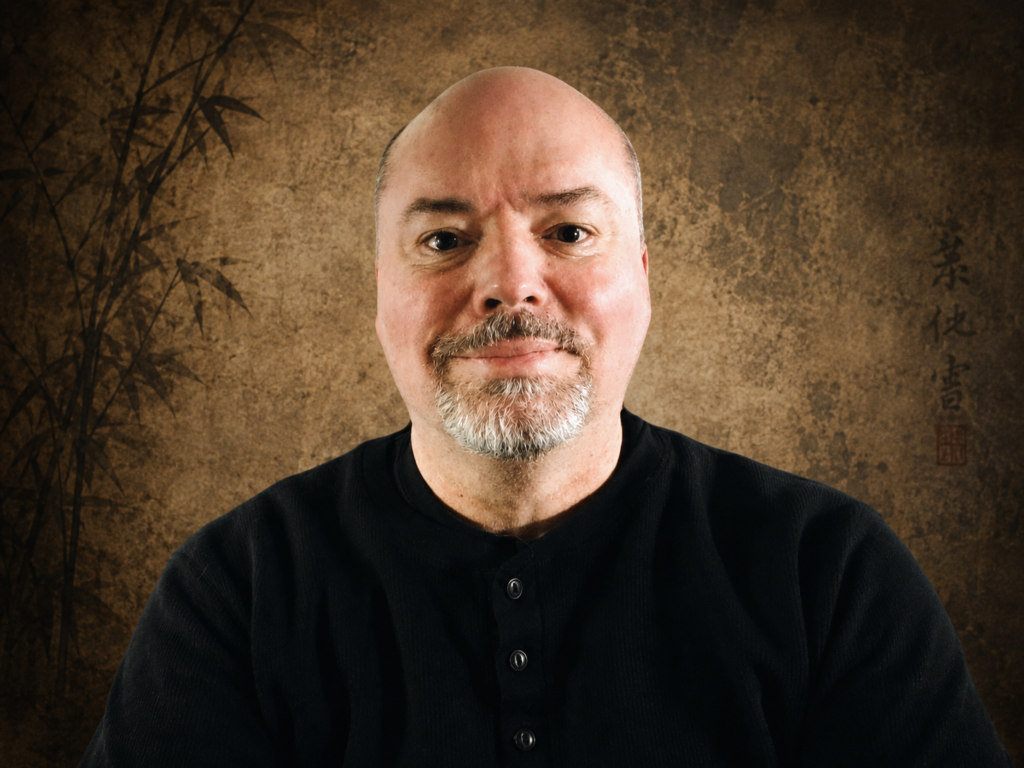 Portrait of Mark V. Wiley, martial artist, author, and researcher, on a warm textured background.