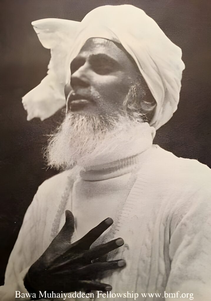 Bawa Muhaiyaddeen with his hand over his heart, illustrating his teachings on the inner heart and spiritual transformation.