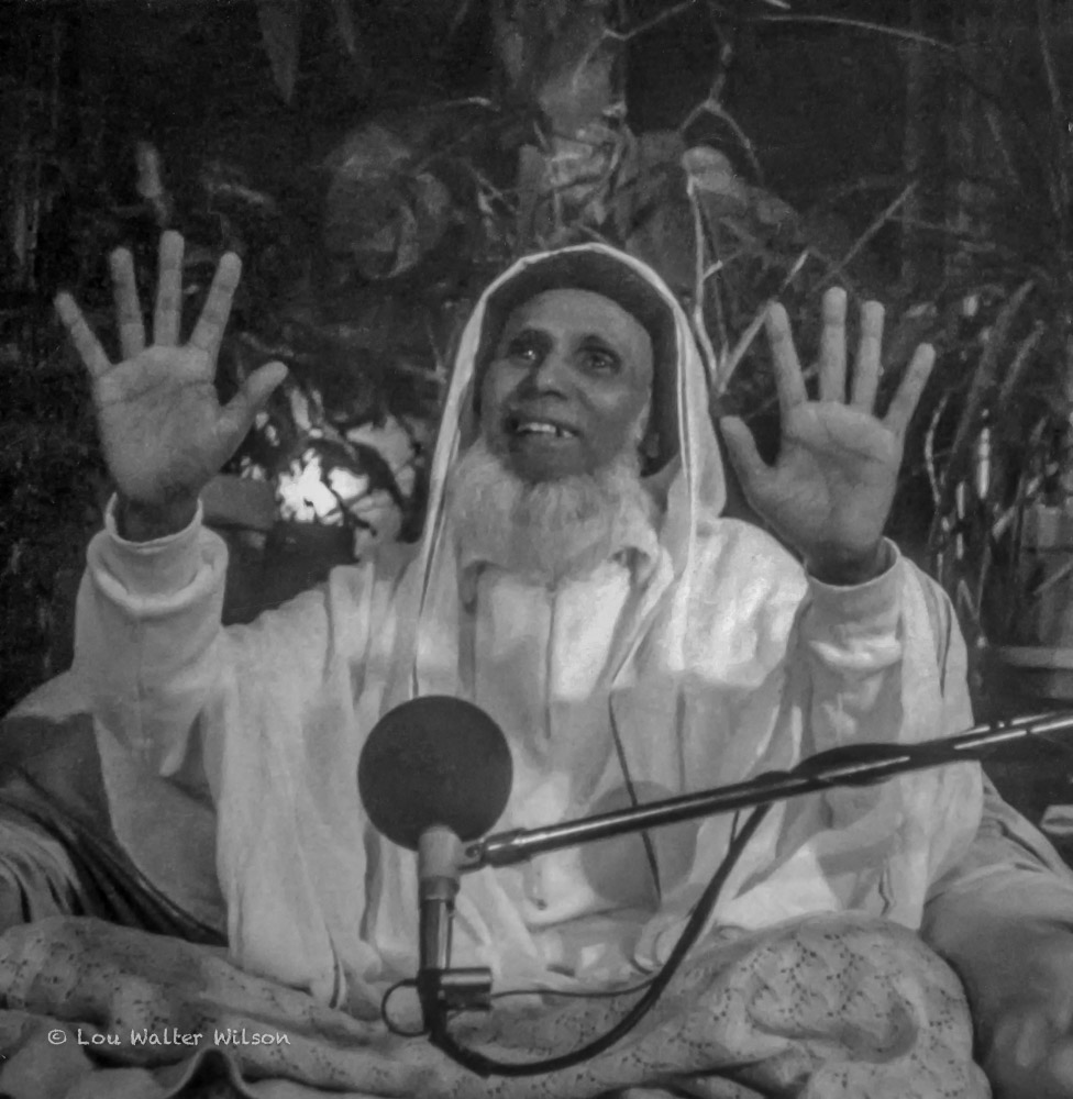 Bawa Muhaiyaddeen raising both hands while teaching about heaven and hell as inner states of consciousness.