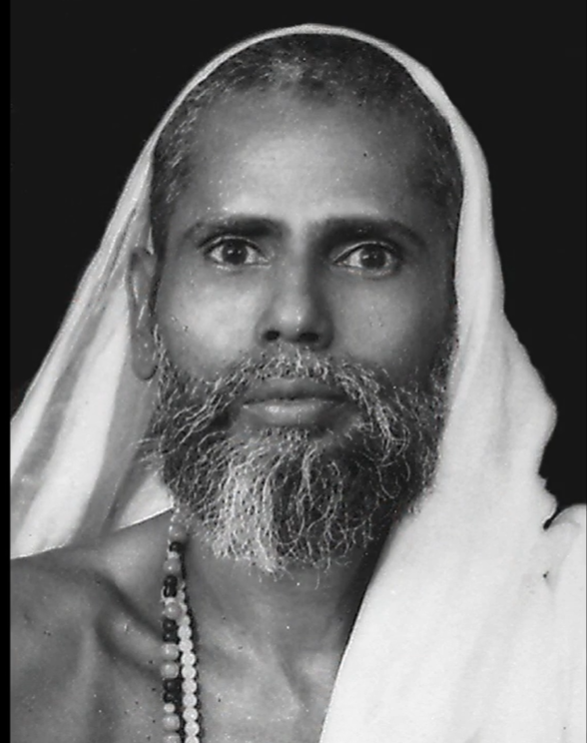 Black-and-white portrait of Bawa Muhaiyaddeen, the Sri Lankan Sufi teacher, wearing a white shawl and prayer beads.