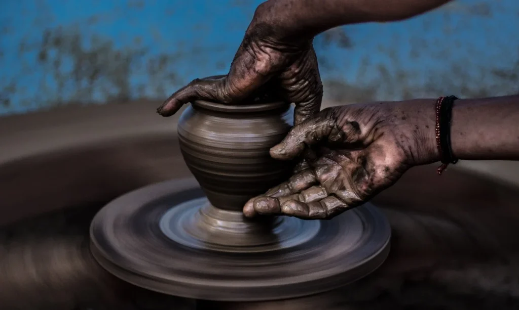 A potter shaping clay on a spinning wheel, illustrating embodied practice, adaptive skill, and the transformative process of learning through continuous adjustment.