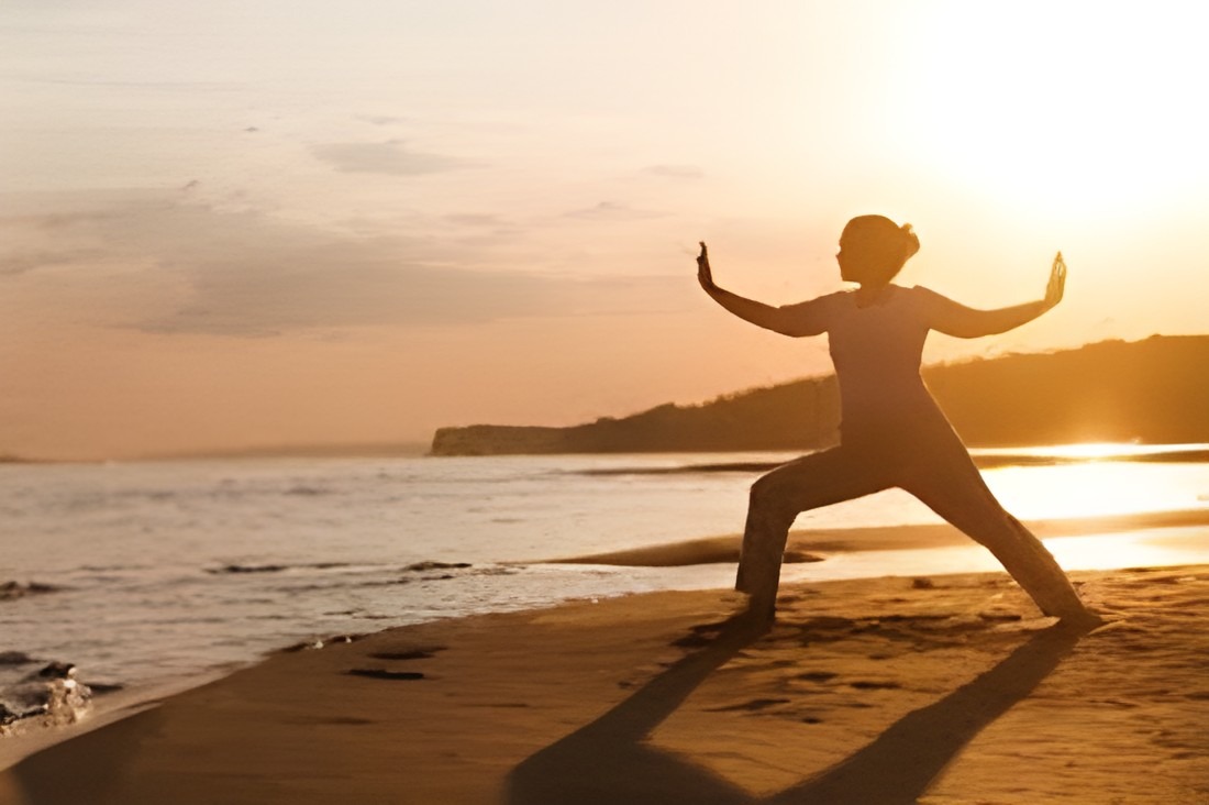 Tai Chi practitioner performing a movement sequence at sunrise, illustrating embodied practice, awareness, balance, and integration.