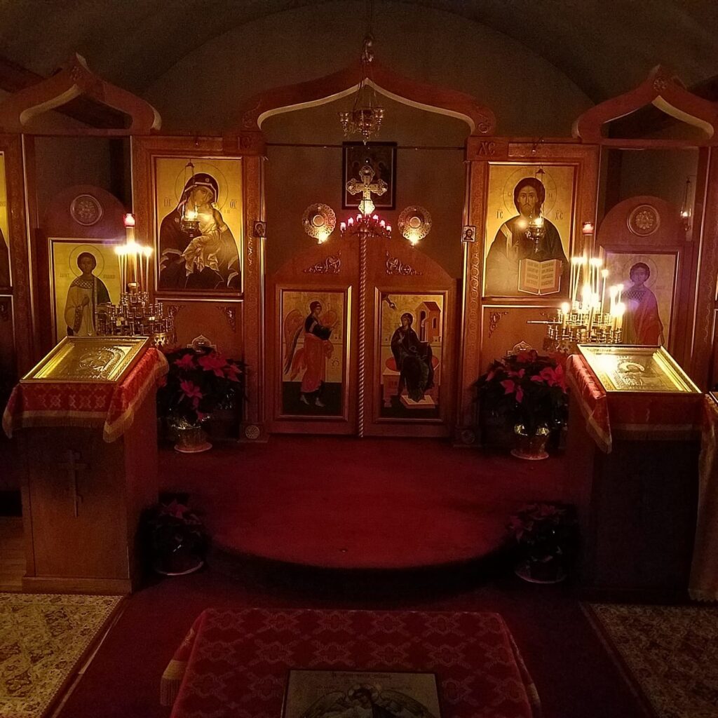 Candlelit Orthodox church interior with icons, prayer candles, and iconostasis, reflecting the contemplative tradition of watchfulness and prayer.