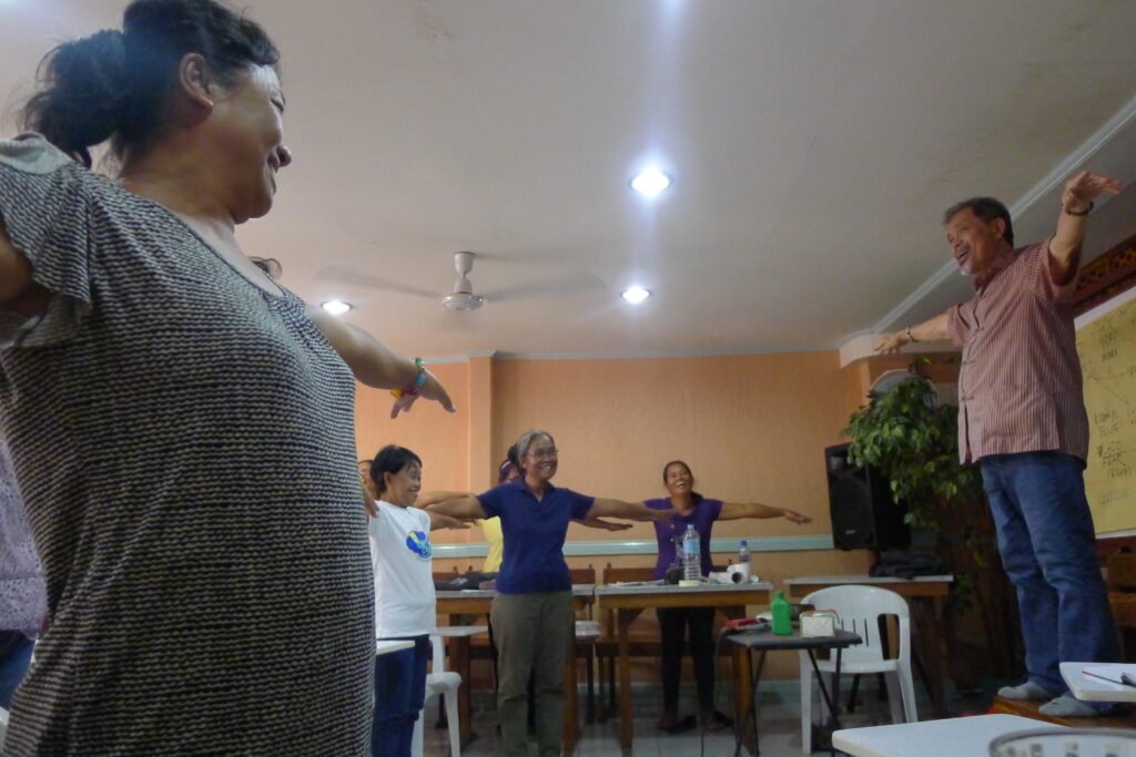 Grandmaster René Navarro standing on a table while leading an internal cultivation workshop with women in Guiuan, Samar, Philippines, following a devastating typhoon.