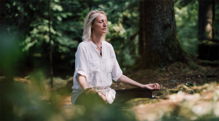 Woman sitting in meditation outdoors, illustrating the problem with Garden Statue Meditation and the need for embodied awareness.
