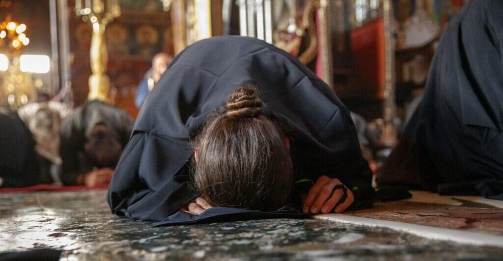 Orthodox Christian worshipper making a full prostration during spiritual practice of prayer