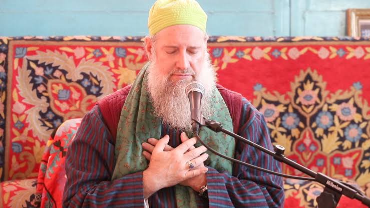Shaykh Burhanuddin Herrmann seated with his hands over his heart during spiritual practice