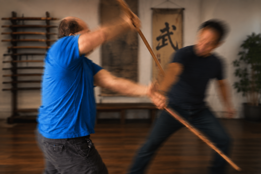 Mark V. Wiley sparring with an opponent in eskrima stick fighting, capturing a moment of perception, awareness, and immediate response.