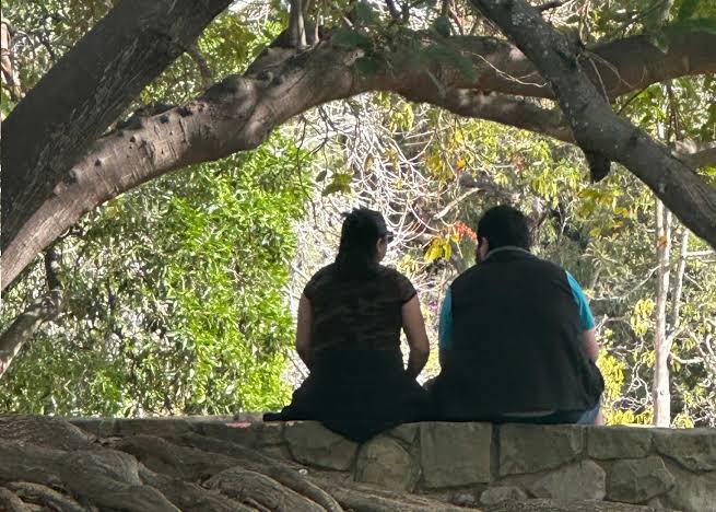 Two people sitting together beneath a tree, illustrating how relationship and interaction become part of embodied practice.